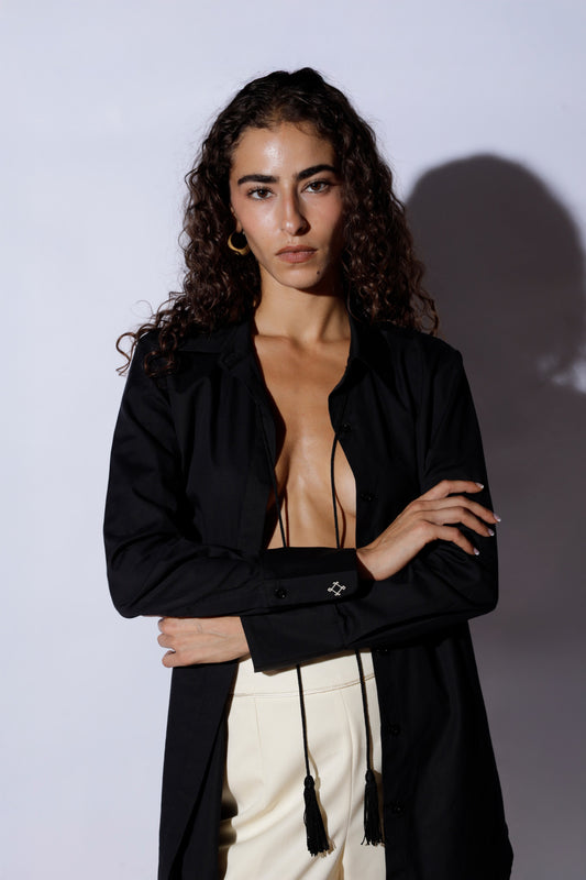 Woman wearing a black open-front blouse with tassels on a white background
