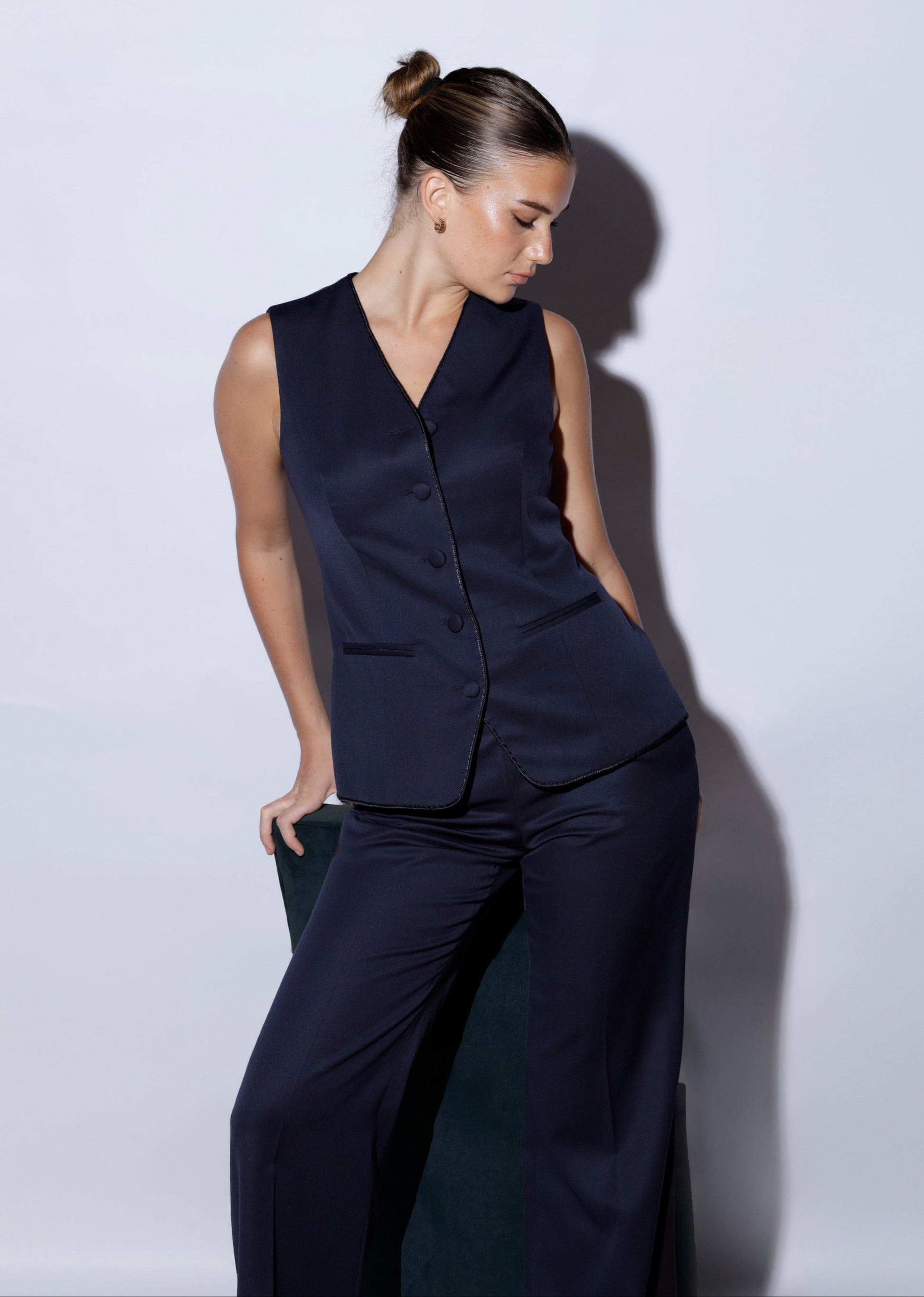 Woman wearing a navy blue sleeveless top and pants against a white background 100% wool navy blue suit