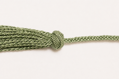 Green braided tassel on a white background
