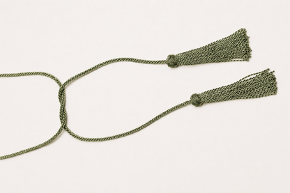 Green braided necklace with tassels on a white background