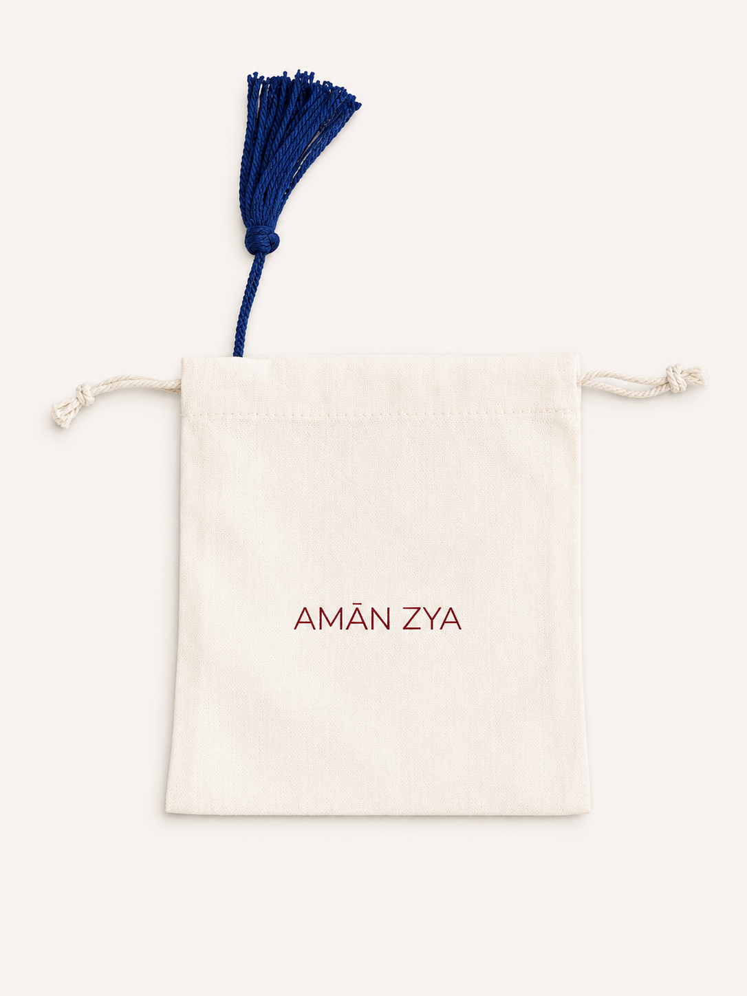 Beige drawstring pouch with 'AM×ó ZYA' branding on a white background
