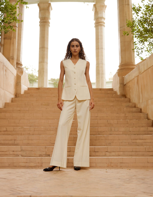 Woman in a Ivory suit standing on stone steps with classical architecture in the background