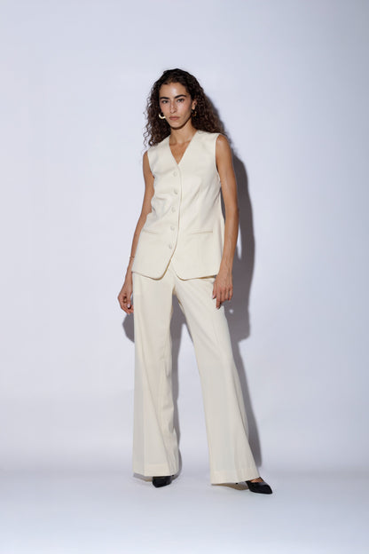Woman wearing a white suit standing against a plain background