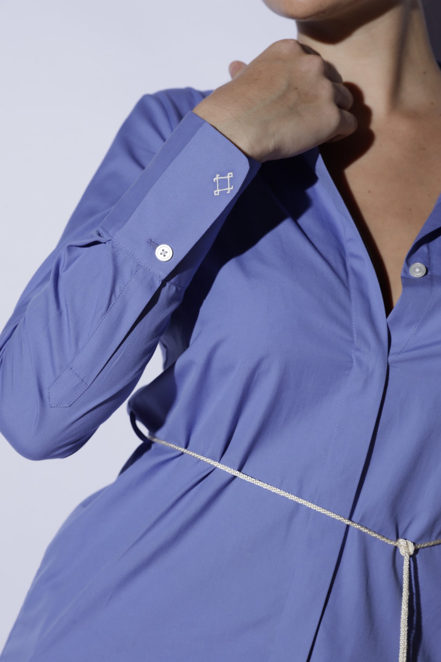 Close-up of a person wearing a blue shirt with a white background