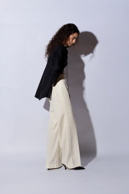 Woman wearing a black top and white pants against a white background
